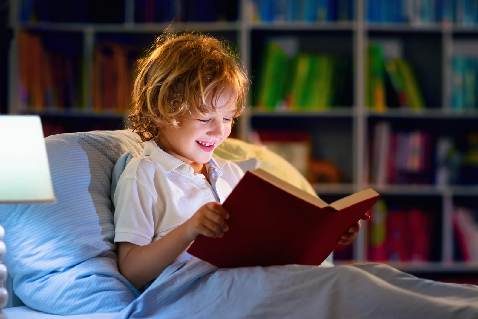 Un jeune garçon lit avec plaisir dans son lit